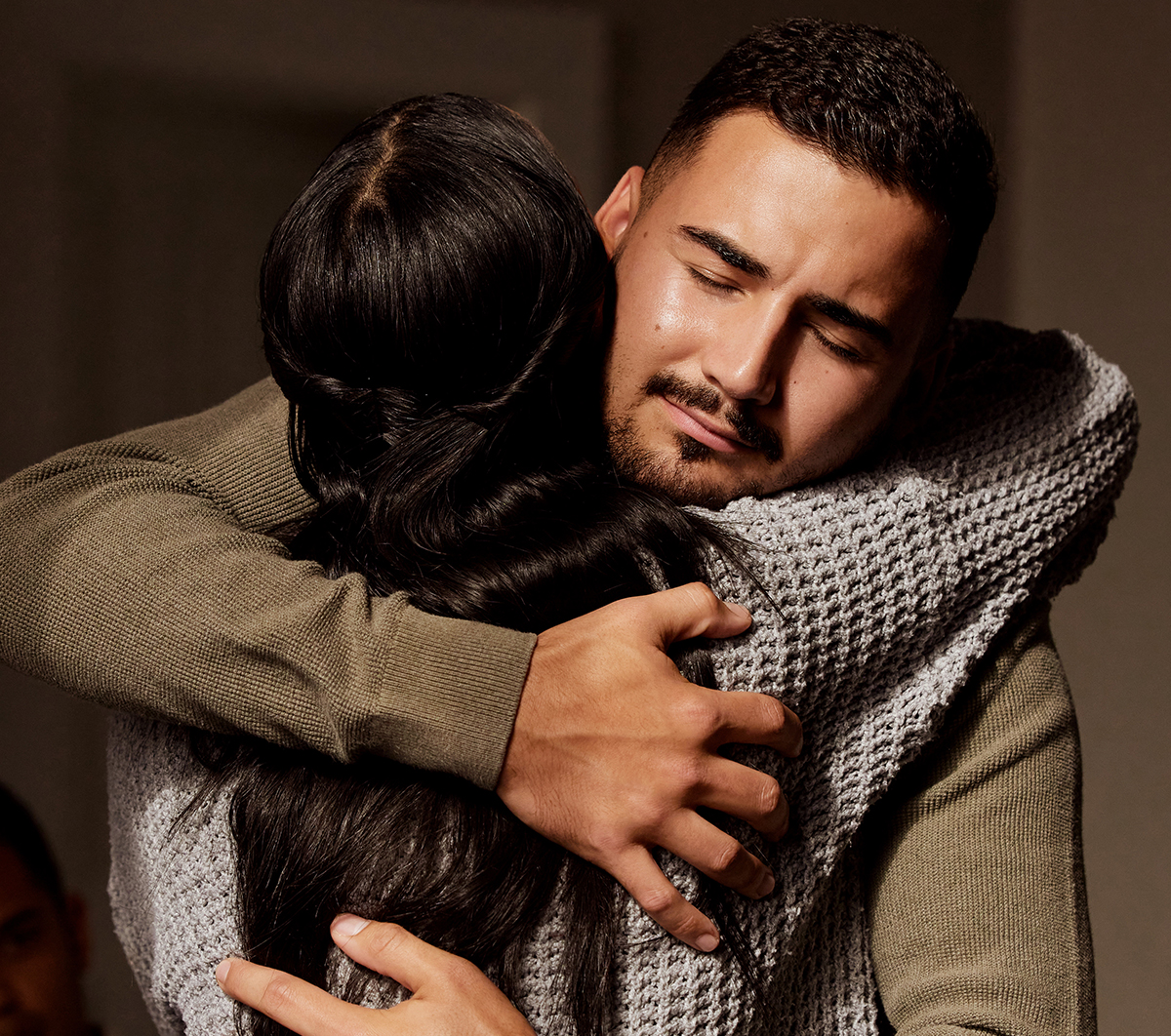Two people embracing warmly, conveying comfort and connection indoors.