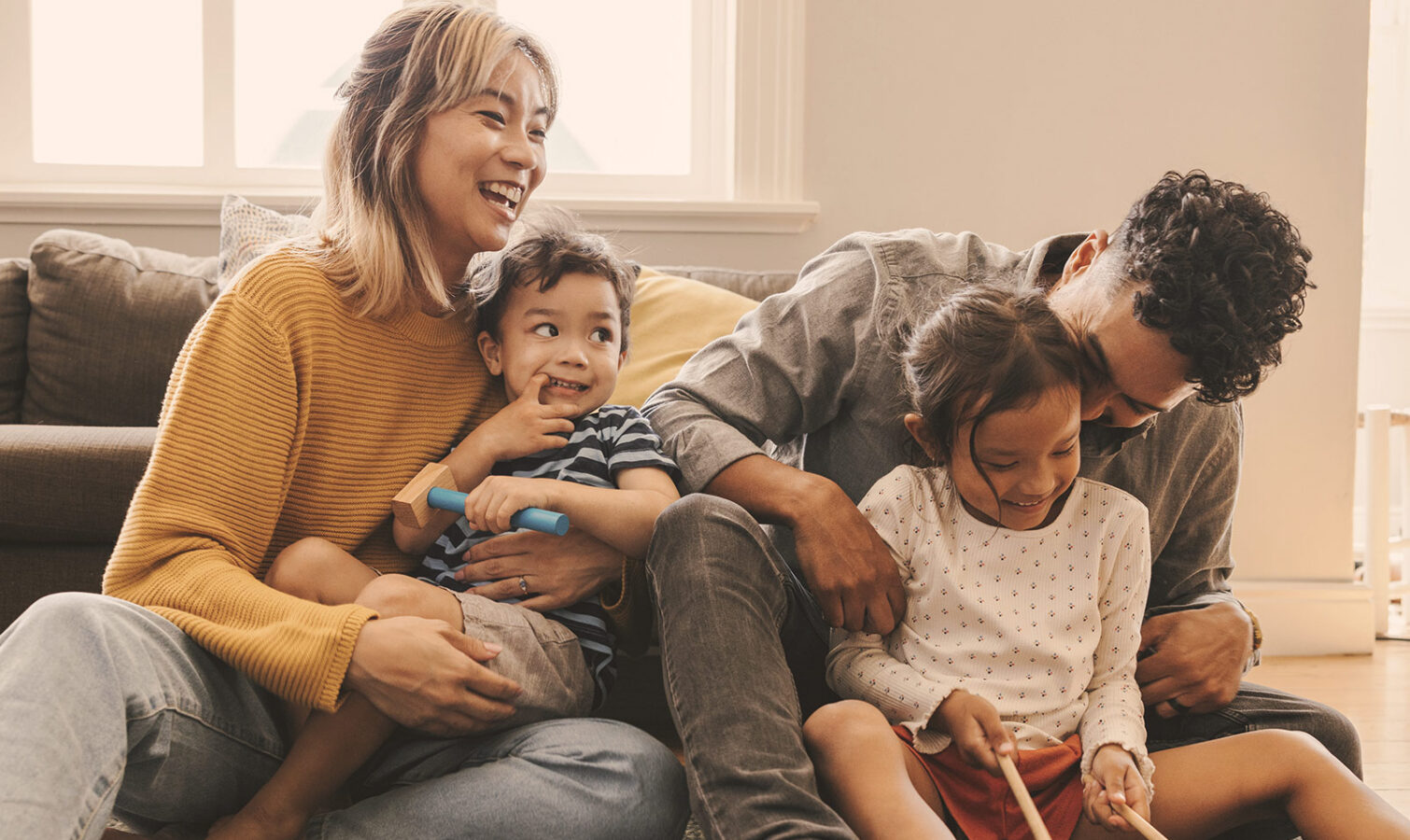 Happy family playing together at home on a cozy sofa.